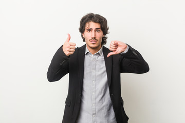 Young business man against a white background showing thumbs up and thumbs down, difficult choose concept