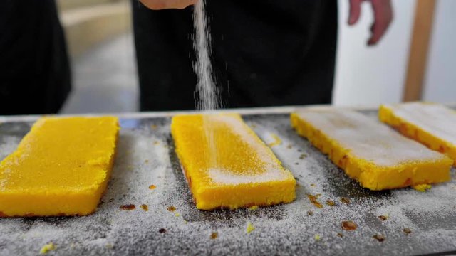 Mano espolvoreando az&uacute;car sobre tableta de turr&oacute;n de yema