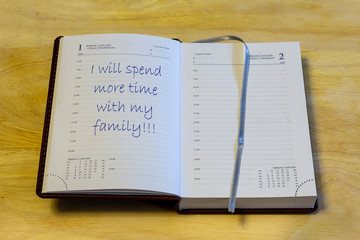 The diary is on the table. The diary is open on the first of January page. On the page it is written: "I will spend more time with my family!!!".