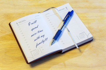 The diary is on the table. The diary is open on the first of January page. On the page it is written: "I will spend more time with my family!!!".