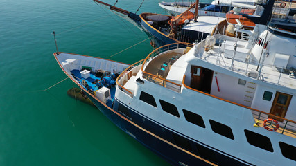 Aerial drone bird's eye top view photo of luxury yacht with wooden deck docked in deep blue waters, Cyclades, Greece