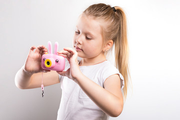 Little girl with a pink camera in hands on a white background