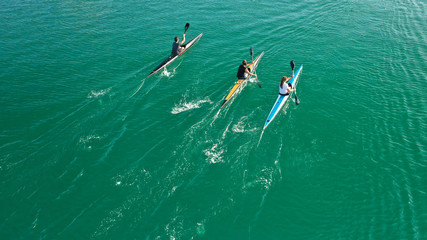 Aerial drone top down photo of fit women competing in sport canoe in tropical exotic lake with emerald waters