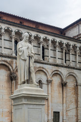 Fototapeta na wymiar The statue of Michael the Archangel and the basilic of San Michele in Foro in Lucca
