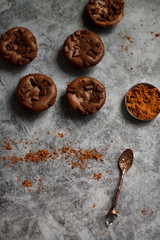 on a dark textured background with chocolate muffins and vintage spoon and cocoa powder.