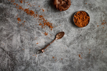 on a dark textured background with chocolate muffins and vintage spoon and cocoa powder.