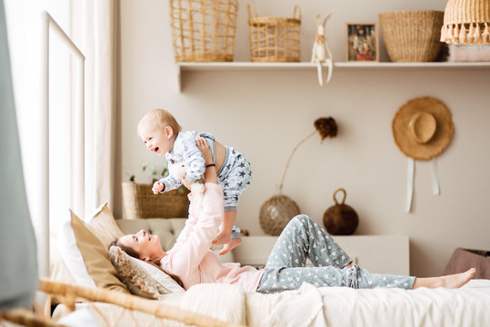 Young mother and son are playing in the bright room of his house. Cute baby boy with his mom. Happy and cute family chatting with baby