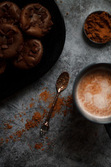 cocoa drink in blue mug with chocolate on dark textured background with chocolate muffins and vintage spoon and cocoa powder.