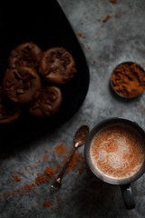 cocoa drink in blue mug with chocolate on dark textured background with chocolate muffins and vintage spoon and cocoa powder.