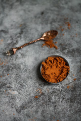 on a dark textured background vintage with a spoon and the cocoa powder.