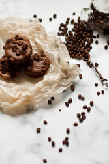 on a light textured marble background, chocolate muffins on parchment paper with a vintage spoon and coffee beans top view.