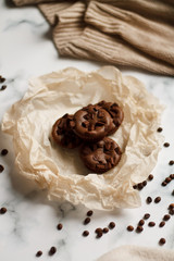 on a light textured marble background, chocolate muffins on parchment paper with a vintage spoon and coffee beans top view.