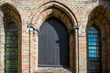 Detail of medieval church façade featuring gothic windows and brick wall in Bruges, Belgium. Travel or medieval background. 