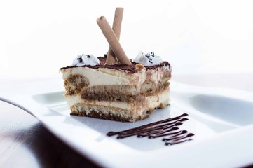 provocative cold cream and chocolate cake, with biscuit sticks and dark chocolate decoration plate