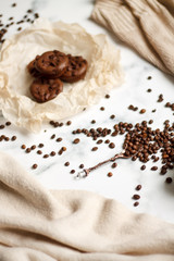 on a light textured marble background, chocolate muffins on parchment paper with a vintage spoon and coffee beans top view.