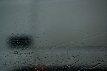 Water drops on the glass of a car, window texture, selective focus, raindrops and blurred background