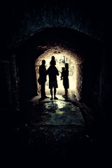 light at end of the tunnel, an artistic monochromatic street photo with a group of people standing in a narrow passage with bright light in the background, old architecture, dark mood, book cover