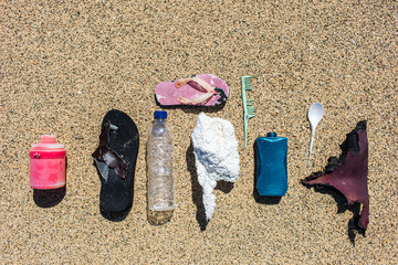 Various types of plastic waste collected on the beach. Single-use spoons, rubber shoes, different...