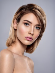 Fototapeta premium Beautiful young woman with clean skin face looks to the camera