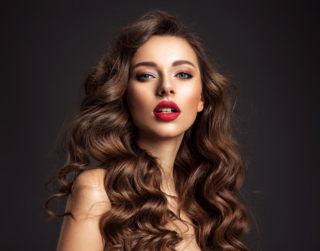Beautiful face of young woman with red lipstick. Portrait of a stunning sexy girl looks at camera. Attractive model with stylish makeup.  Closeup portrait of a caucasian female.