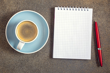 Coffee cup and notepad for notes on stone background with copy space, top view