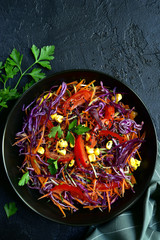 Red cabbage salad cole slaw with carrot and cucumber in a bow. Top view.
