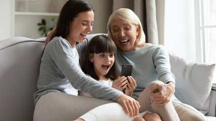 Elderly grandmother her adult daughter and granddaughter having fun online