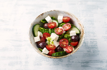 Salad with Kalamata Olives, Cucumber Cherry Tomatoes and Feta Cheese on bright wooden Background. Healthy Snack Idea. Close up.