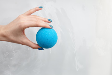 Woman's hand putting bath bomb into water