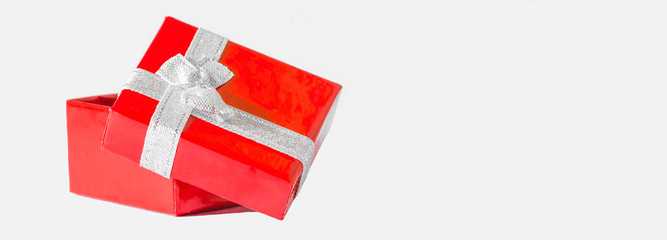 Fototapeta na wymiar Red gift box with silver ribbon bow, isolated on white, background panorama long with space for text