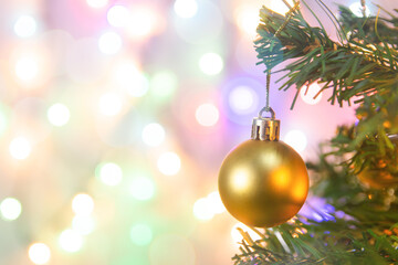 Christmas decoration. Hanging gold balls on pine branches Christmas tree garland and ornaments over abstract bokeh background with copy space.