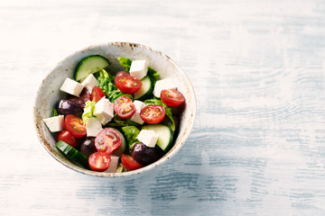 Salad with Kalamata Olives, Cucumber Cherry Tomatoes and Feta Cheese on bright wooden Background....