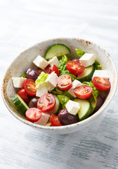 Salad with Kalamata Olives, Cucumber Cherry Tomatoes and Feta Cheese on bright wooden Background. Healthy Snack Idea. Close up.