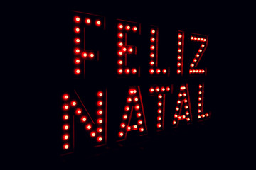 Fototapeta na wymiar Merry christmas written in portuguese on neon red light black background