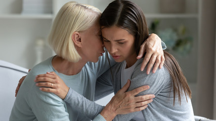 50s mother hugs calms grownup daughter telling words supporting her