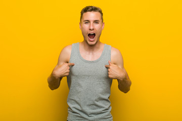 Young caucasian sport man surprised pointing with finger, smiling broadly.