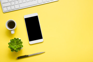 Yellow desk office with laptop, smartphone and other work supplies with cup of coffee. Top view...