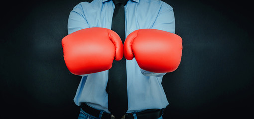 A man, a businessman wearing a shirt, tie is wearing boxing gloves. The concept of fighting in the...