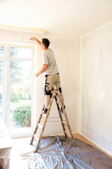 Shot of young man painting the aparmtent's wall