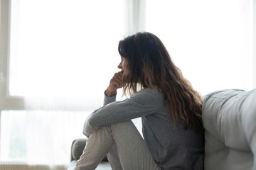 Woman seated on couch lost in sad thoughts about divorce