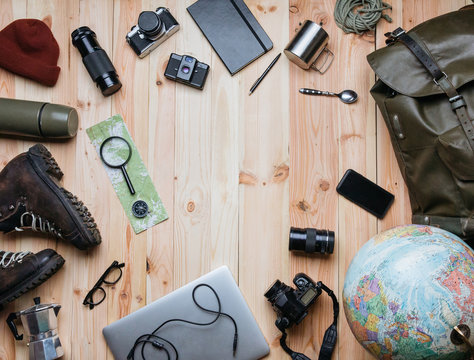 Creative arrangement of travel photography equipment on light raw wooden planks background