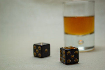 Glass with cognac on a light background with dices