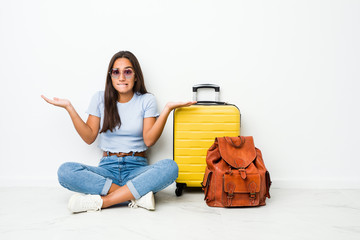 Young mixed race indian woman ready to go to travel confused and doubtful shrugging shoulders to...