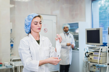 Young nurse preparing to wear protective mask and help surgeon with operation