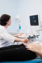 Doctor performing an ultrasound scan on pregnant woman