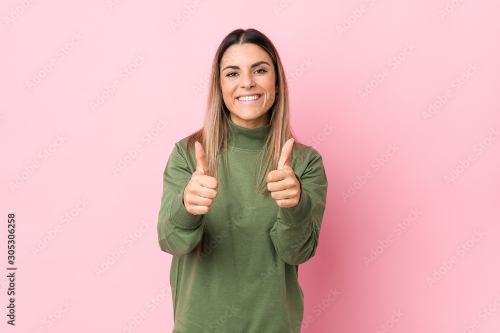 Wall mural young caucasian woman isolated with thumbs ups, cheers about something, support and respect concept.