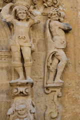 Weathered historical stone figures attached to a stone wall in Mazara del Vallo, Sicily, Italy