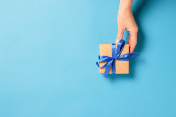 Female hand holds, takes, get a gift on a blue background. Concept gift, wedding, valnetina day....