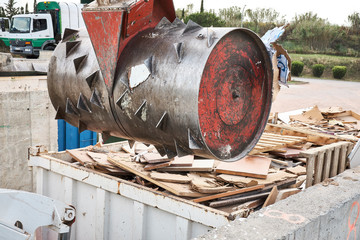 Waste garbage compactor working on a dumpster bin in an outdoors municipal public dumb collector