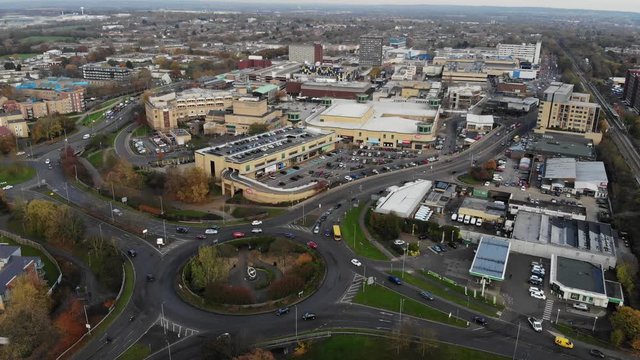 Reverse aerial view moving away from Basildon city center and traffic going through a roundabout at sunset on an autumn day
